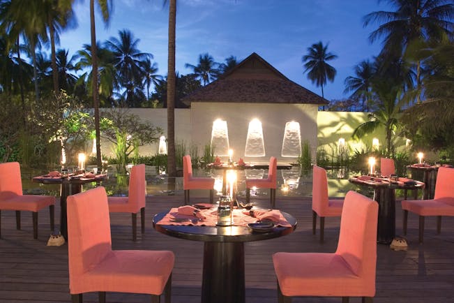 Evason Hua Hin Resort Thailand The Other Restaurant outdoor dining pink chairs pond palms trees night time