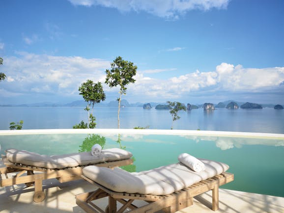 Two sun beds laid out by an infinity pool looking out over the sea