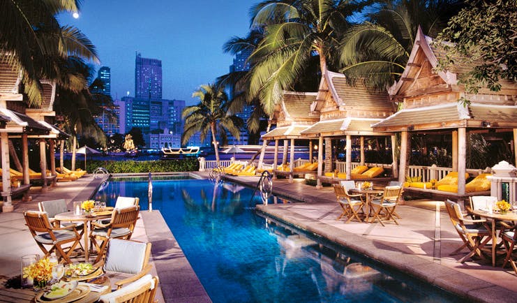 The Peninsula Bangkok Thailand outdoor pool loungers wood pagodas terrace dining city views