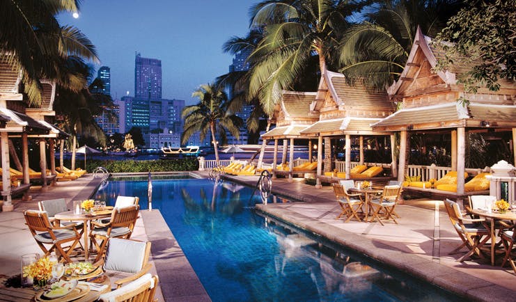The Peninsula Bangkok Thailand outdoor pool loungers wood pagodas terrace dining city views
