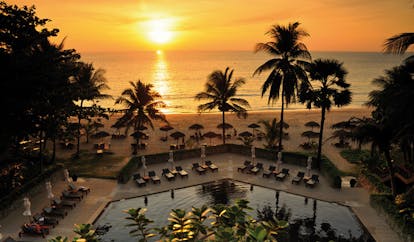 The Surin Phuket Thailand aerial outdoor pool hexagonal pool loungers beach view at sunset