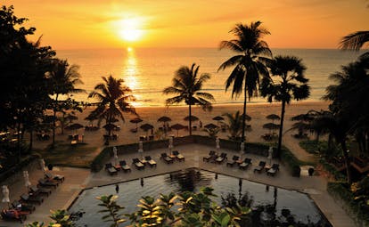 The Surin Phuket Thailand aerial outdoor pool hexagonal pool loungers beach view at sunset
