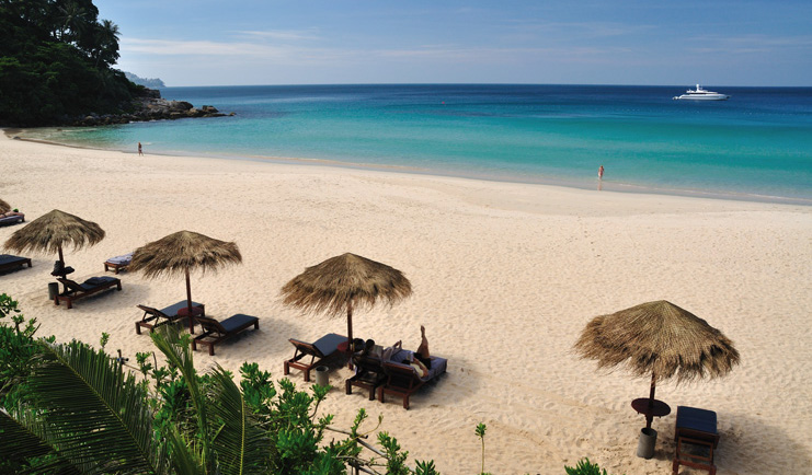 The Surin Phuket Thailand beach lounger with thatched umbrellas