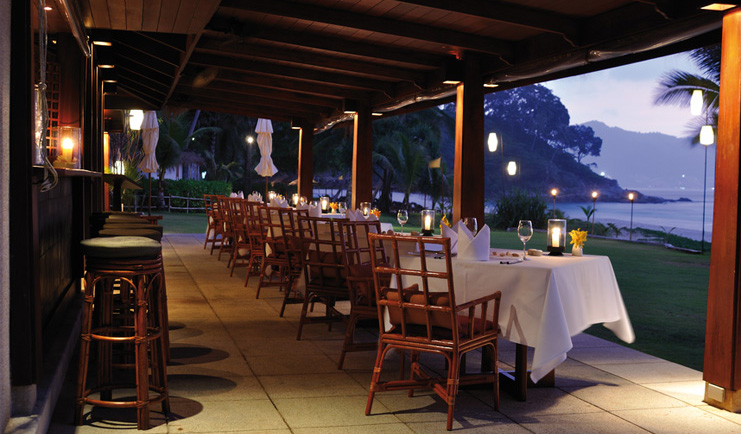 The Surin Phuket Thailand terrace restaurant overlooking lawns beach view at dusk