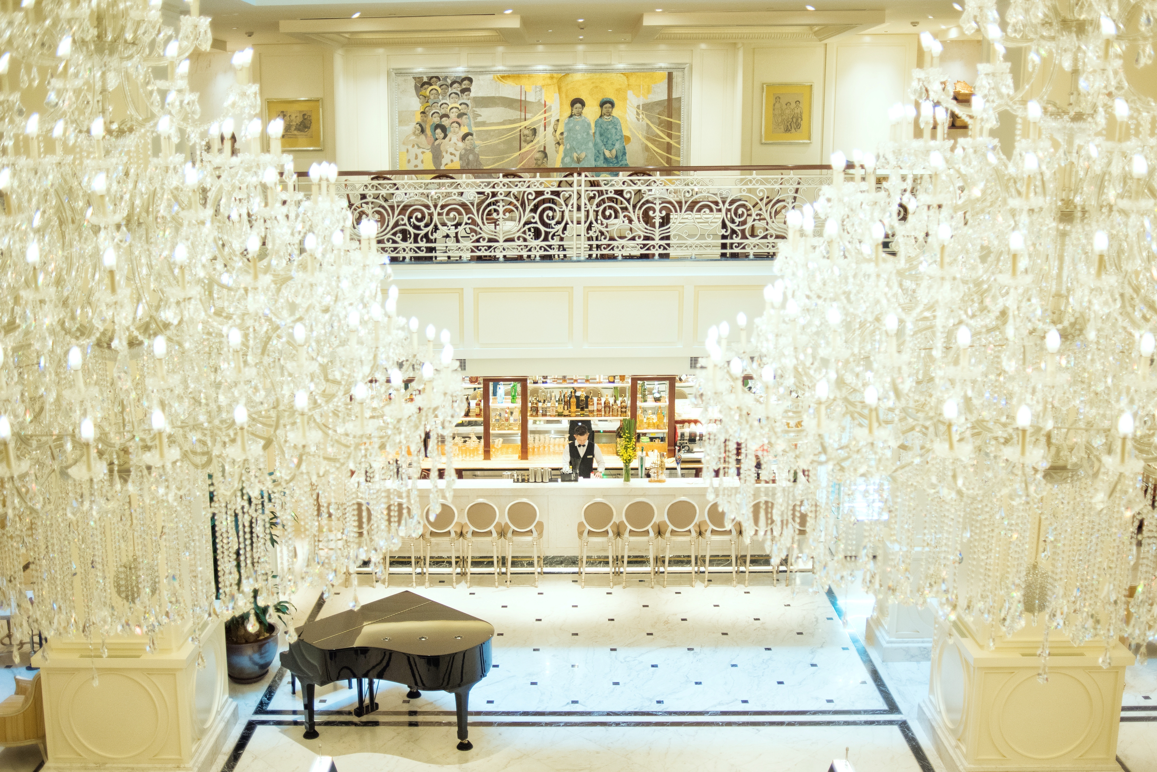 Apricot Hotel atelier bar in lobby, elegant decor, glass chandeliers, grand piano, waiter behind bar