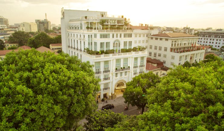 Apricot Hotel exterior, grand hotel building, colonial style architecture, trees, city in background