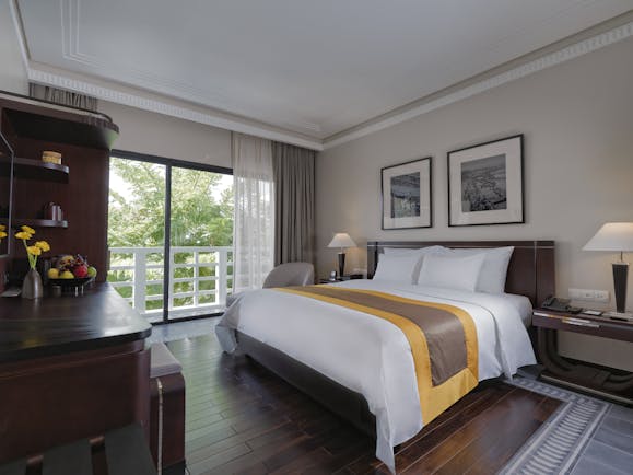 Azerai La Residence superior standard guestroom, bed, french windows leading to balcony, elegant decor