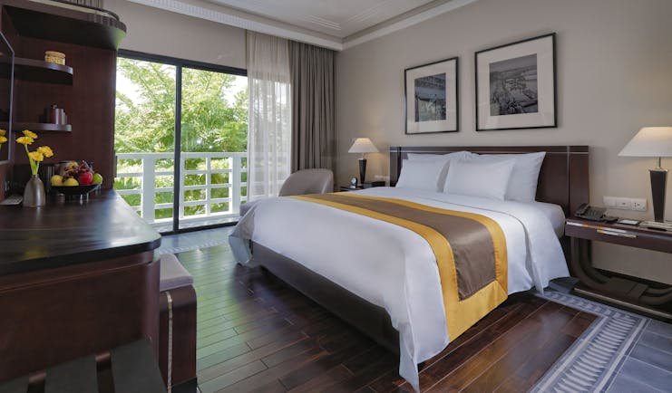 Azerai La Residence superior standard guestroom, bed, french windows leading to balcony, elegant decor