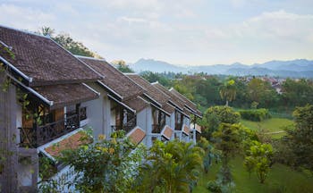 Belmond La Residence Phou Vao exterior, hotel buildings overlooking gardens, mountains in background
