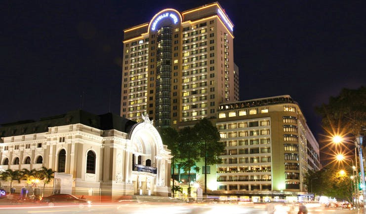 Caravelle Hotel Vietnam exterior night skyscraper next to white theatre like building