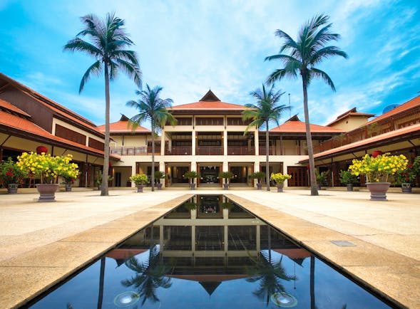 Furama Resort Vietnam building with white portico and two palms behind narrow pool