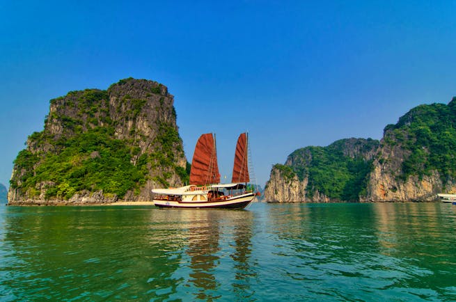 L'Amour Junk boat on water, red sails, rock formation in background