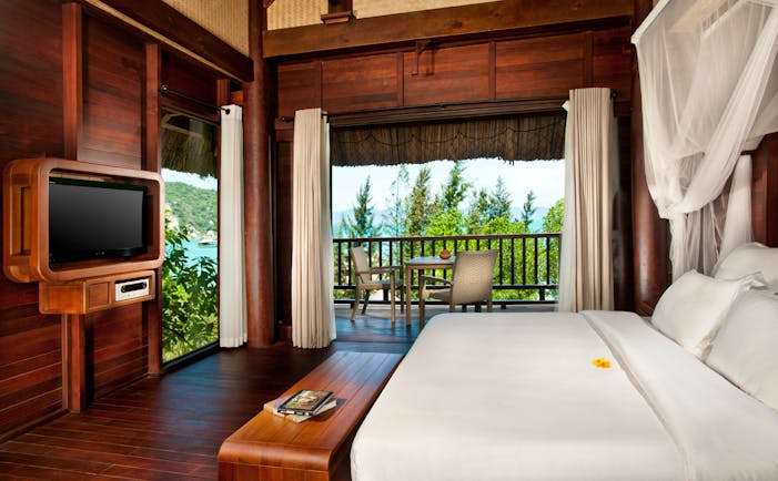 L'Ayla Ninh Van Bay hill rock villa bedroom, double bed with canopy, television, wood panel walls