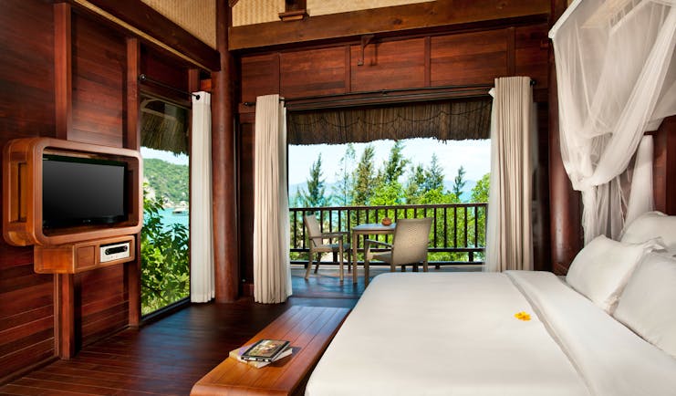 L'Ayla Ninh Van Bay hill rock villa bedroom, double bed with canopy, television, wood panel walls