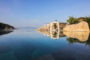 L'Ayla Ninh Van Bay infinity pool with mountains in background, couple meditating on rock