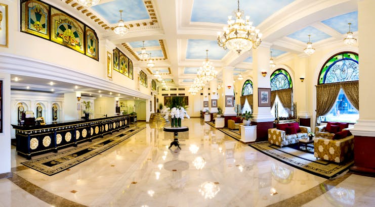 Majestic Hotel Saigon lobby, dark wooden desks, marble floors, chandelier, grand decor