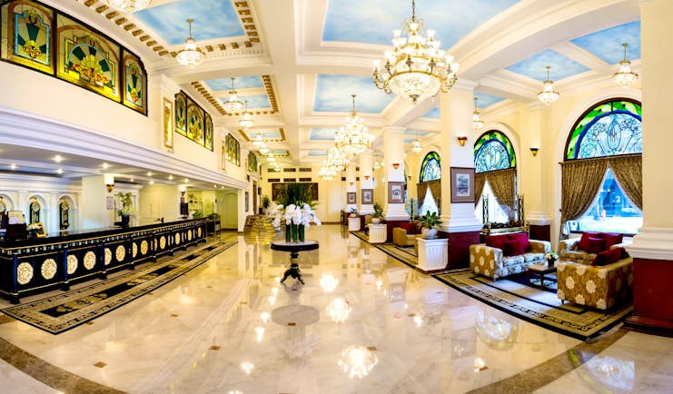 Majestic Hotel Saigon lobby, dark wooden desks, marble floors, chandelier, grand decor