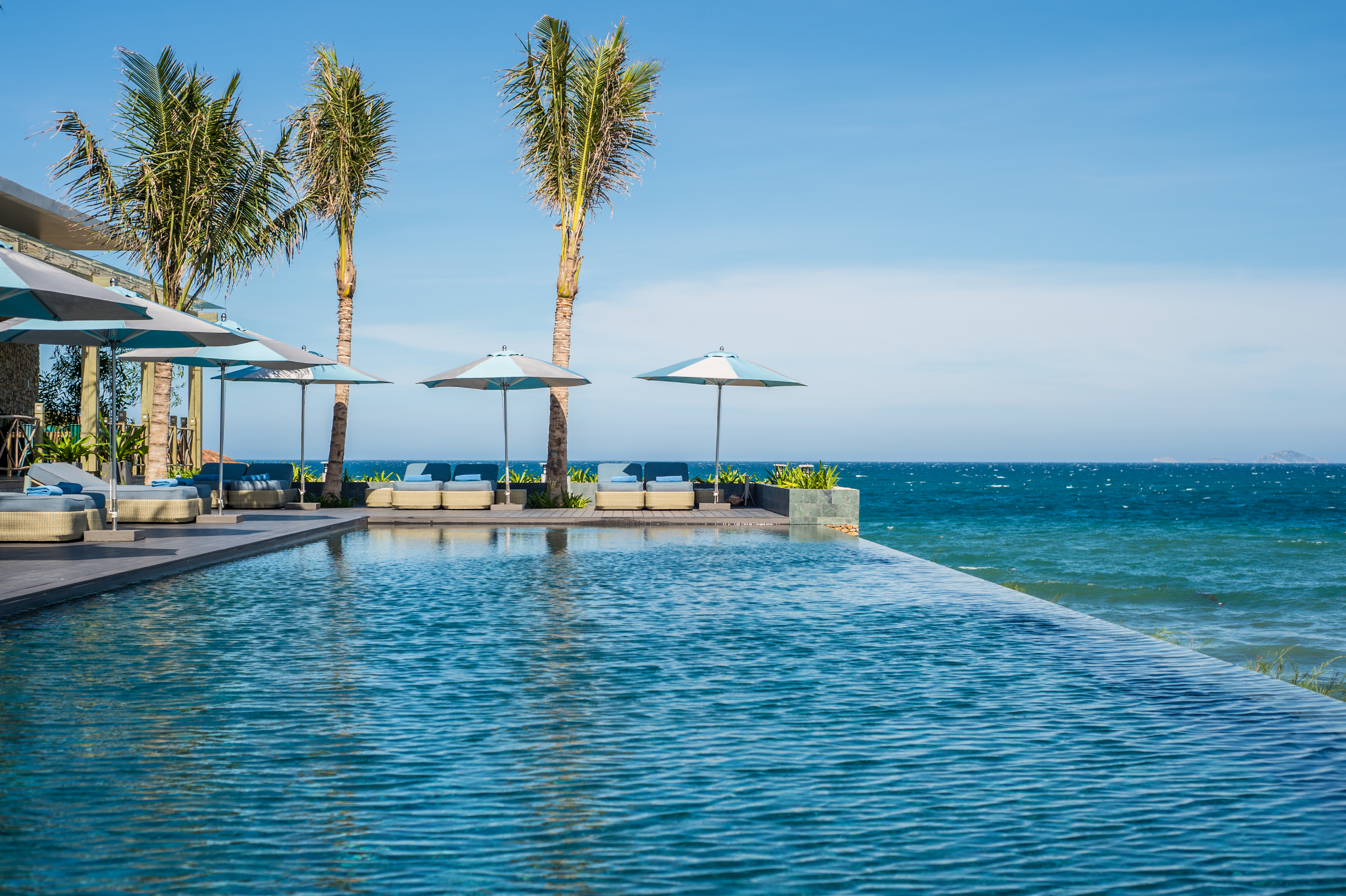 Mia Nha Trang infinity pool, overlooking beach and sea, poolside loungers and umbrellas