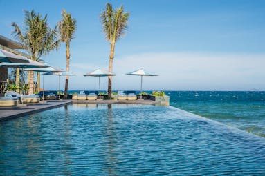 Mia Nha Trang infinity pool, overlooking beach and sea, poolside loungers and umbrellas