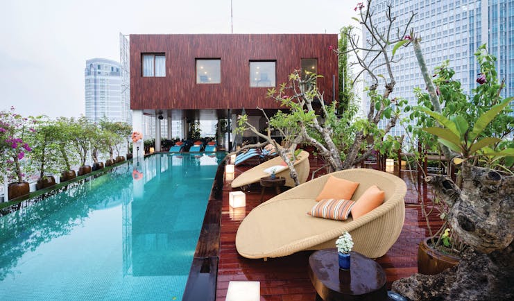 Pool view with large rectangular pool, seating pods set up around on wooden decking and plants
