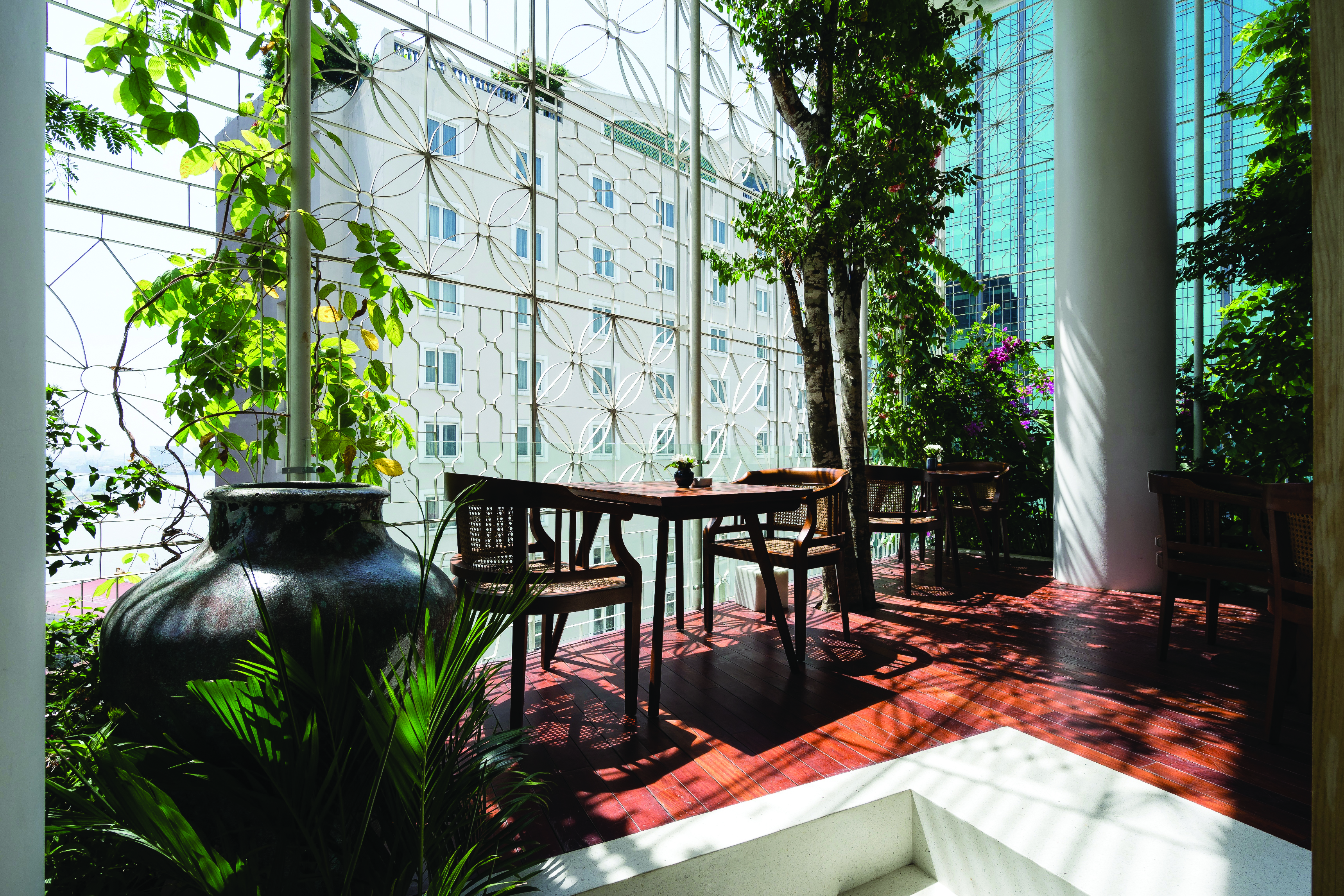 Myst Dong Khoi terrace area with large glass pannelled walls looking over the city, vines growing outside and high bar stool seating areas