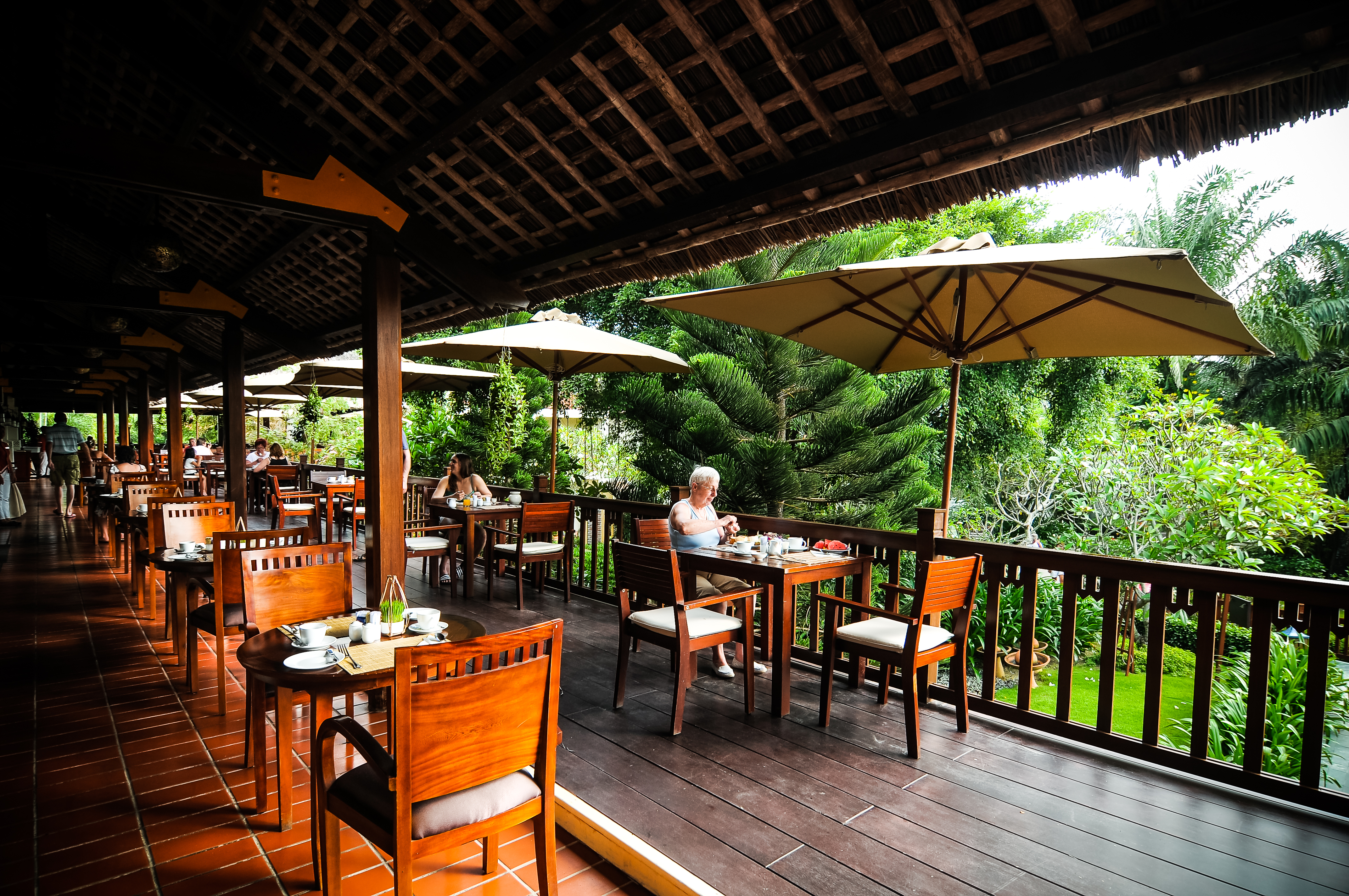 Palm Garden Resort terrace, outdoor dining area, tables, chairs, umbrellas, overlooking garden
