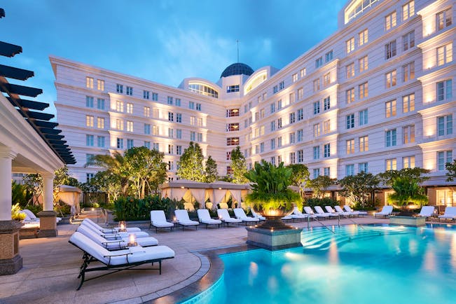 Park Hyatt Saigon pool, sun loungers, trees, hotel building in background