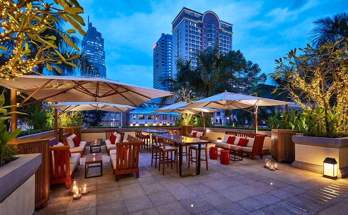 Park Hyatt Saigon terrace, outdoor dining area, tables and chairs covered with umbrellas, city views