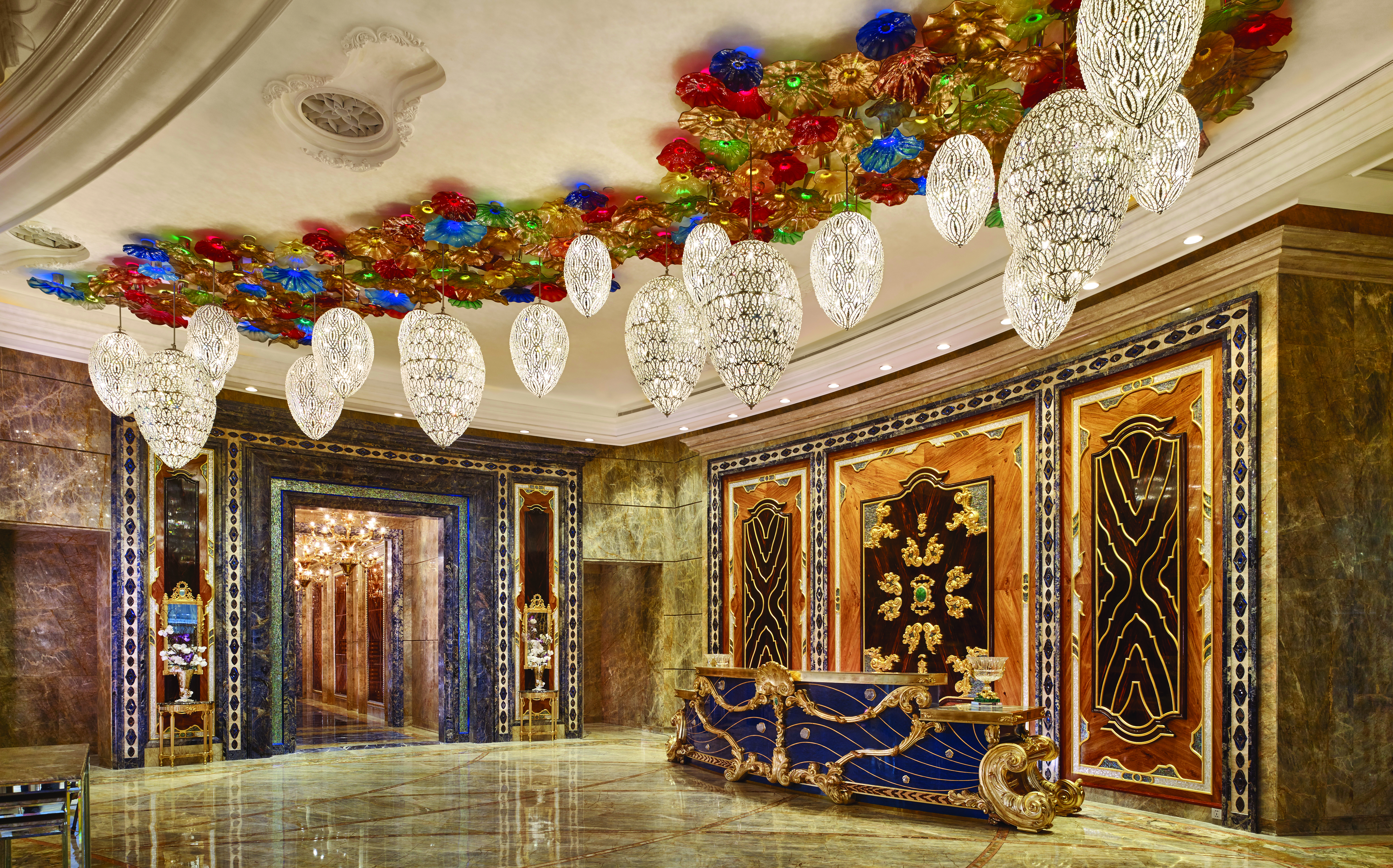 Main lobby at the Reverie Saigon with multiple large chandeliers hanging from the ceiling, gold panelling in the waters and marble floors