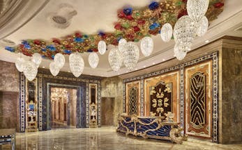 Main lobby at the Reverie Saigon with multiple large chandeliers hanging from the ceiling, gold panelling in the waters and marble floors