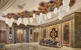 Main lobby at the Reverie Saigon with multiple large chandeliers hanging from the ceiling, gold panelling in the waters and marble floors