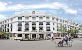 Exterior view of the Saigon Morin hotel with a white front, with large arching windows 