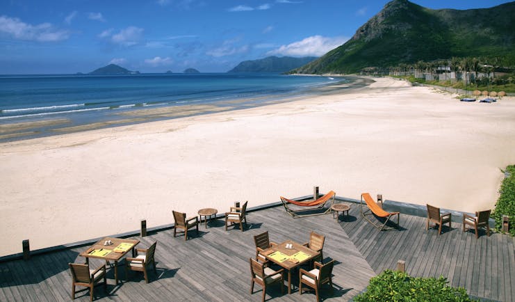 Six Senses Vietnam beach deck terraced seating area on beach front mountains in background