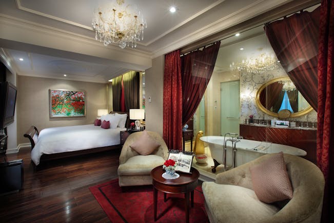 Sofitel Metropole Hanoi grand prestige suite, bed, armchairs, en suite bathroom behind glass wall