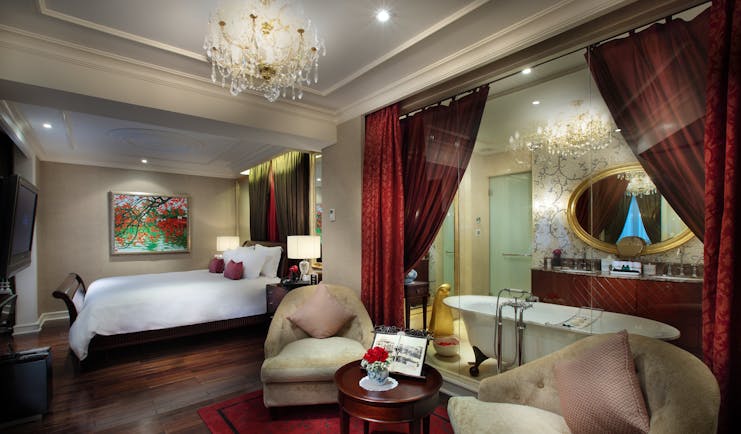 Sofitel Metropole Hanoi grand prestige suite, bed, armchairs, en suite bathroom behind glass wall