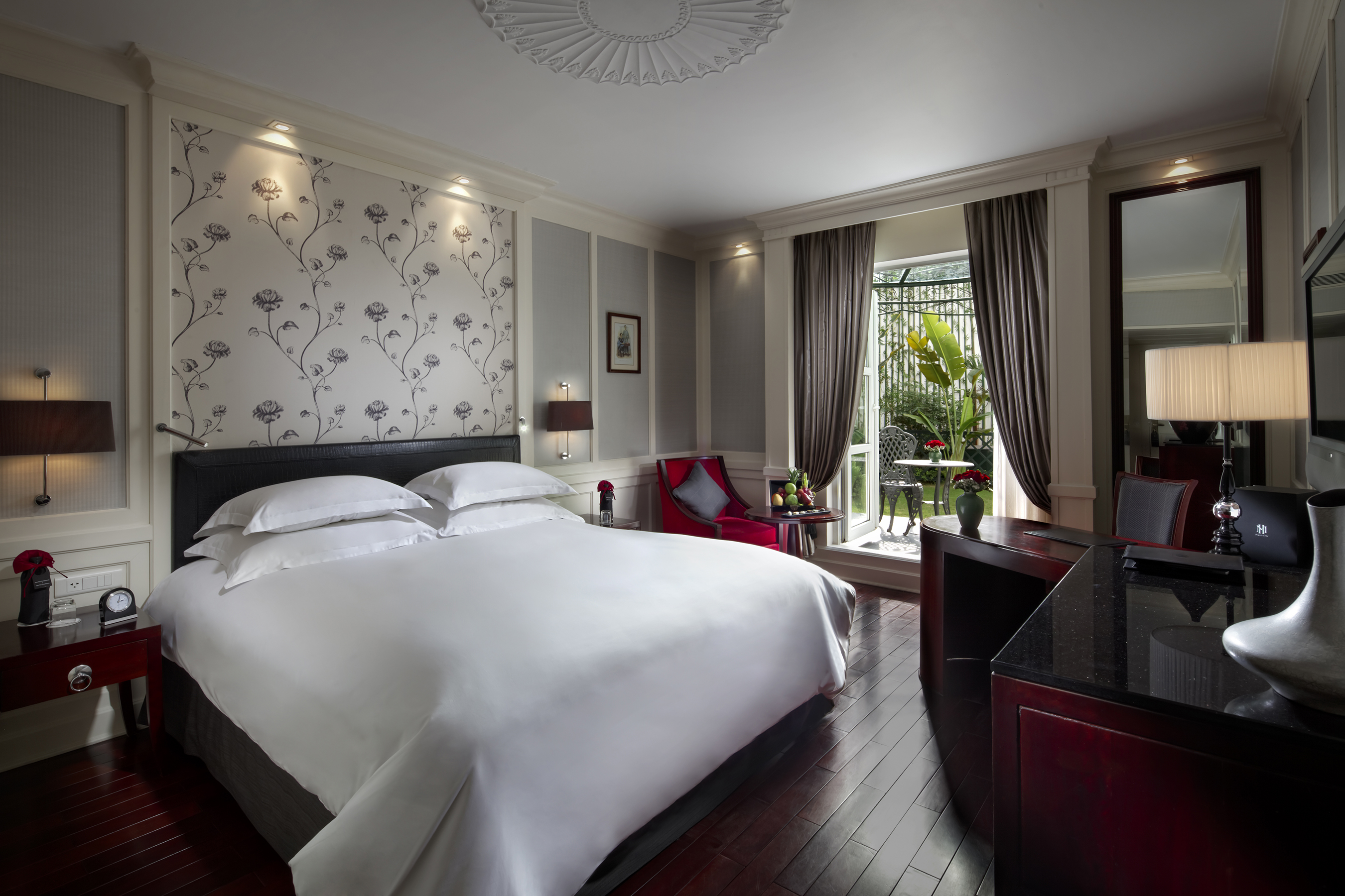 Sofitel Metropole Hanoi premium room, double bed, armchair, doors leading to garden, elegant decor