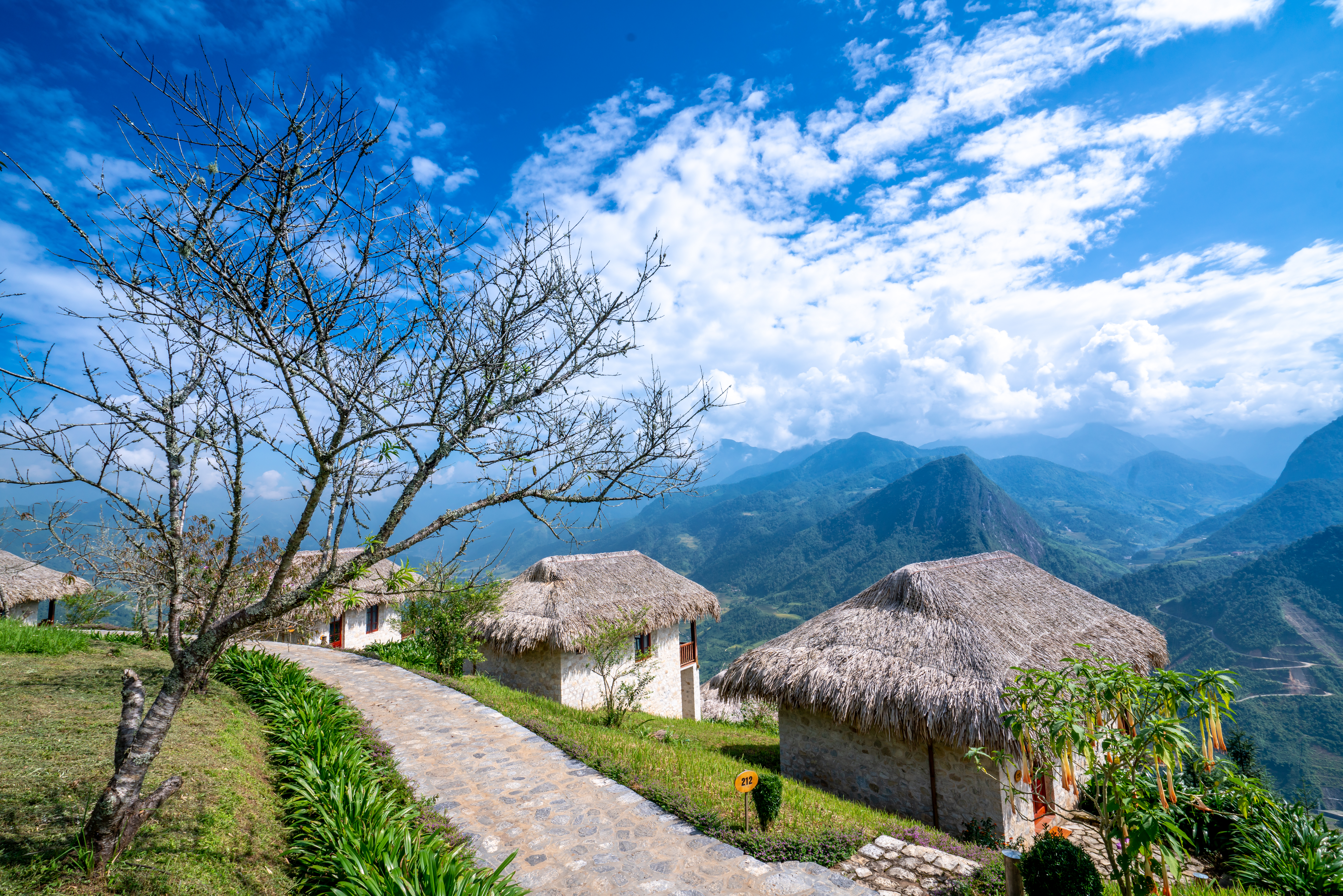 Topas Ecolodge bungalow exteriors, thatched buildings, mountain peaks in background, blue sky, green lawns