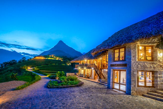 Topas Ecolodge exterior, thatched building, path, mountain in background