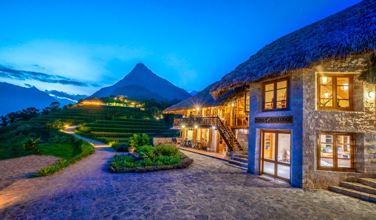 Topas Ecolodge exterior, thatched building, path, mountain in background