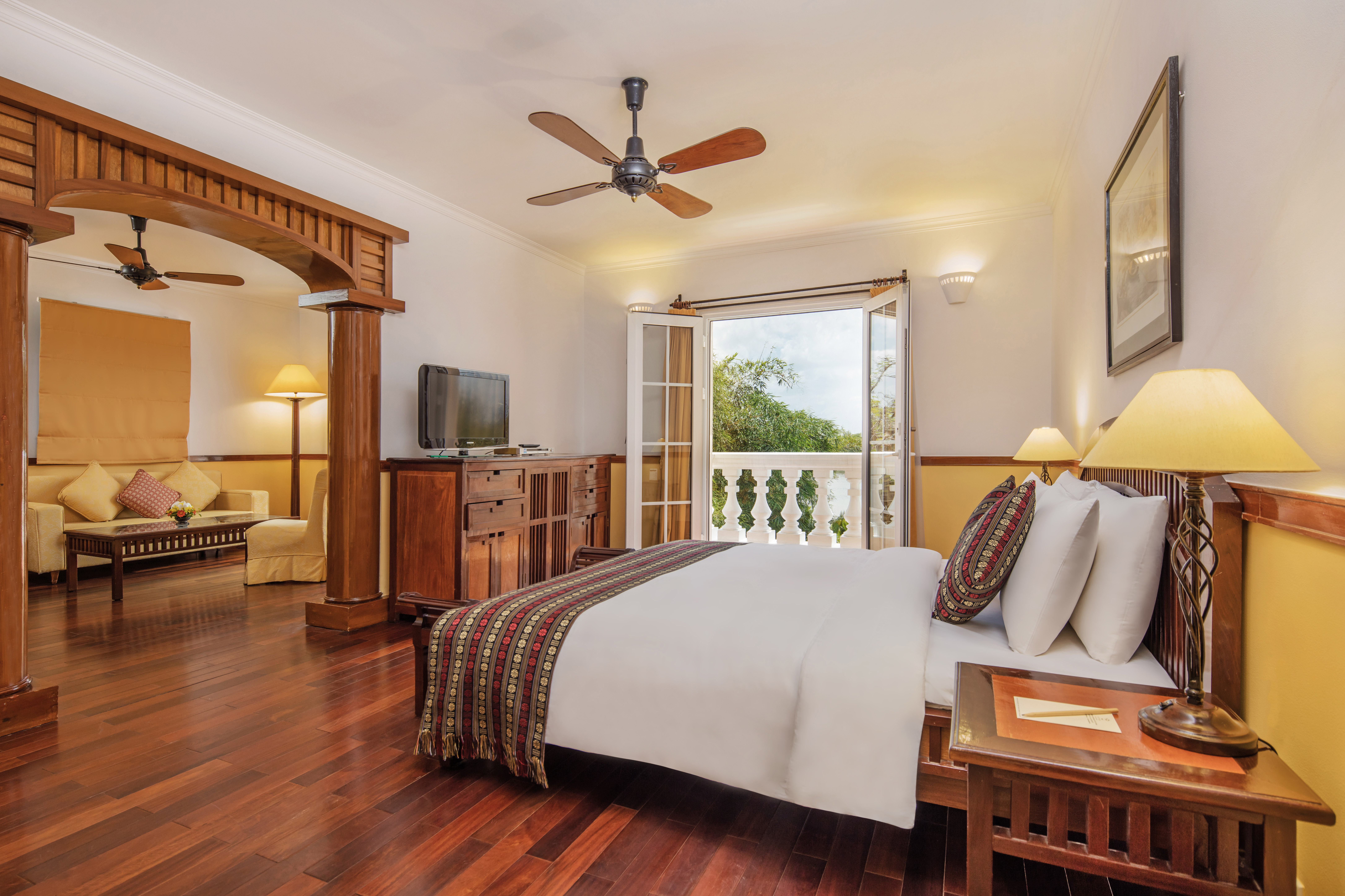 Victoria Can Tho Resort colonial suite, double bed, living area with sofa, modern decor, balcony