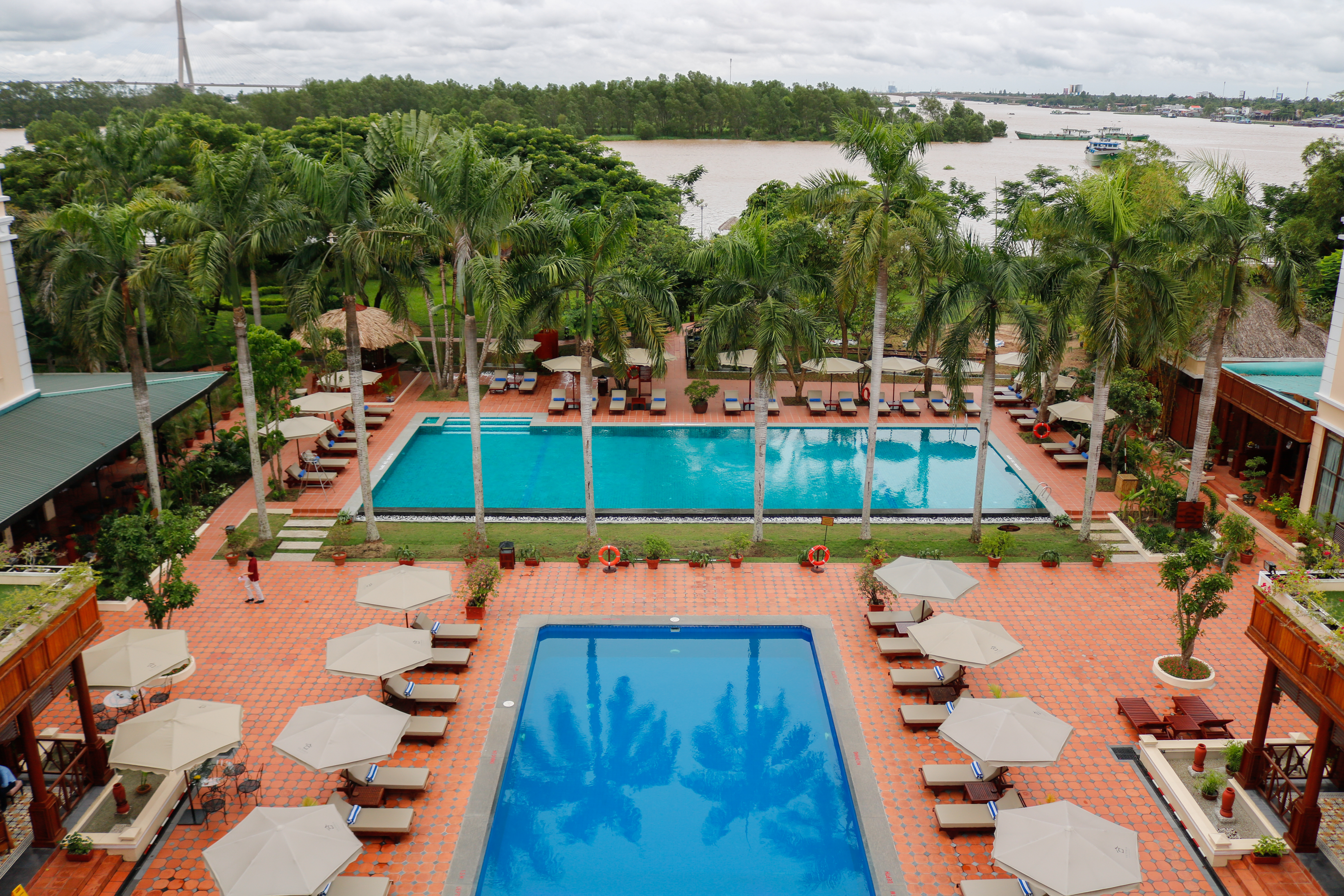 Victoria Can Tho Resort pools, sun loungers, palm trees, bay in background