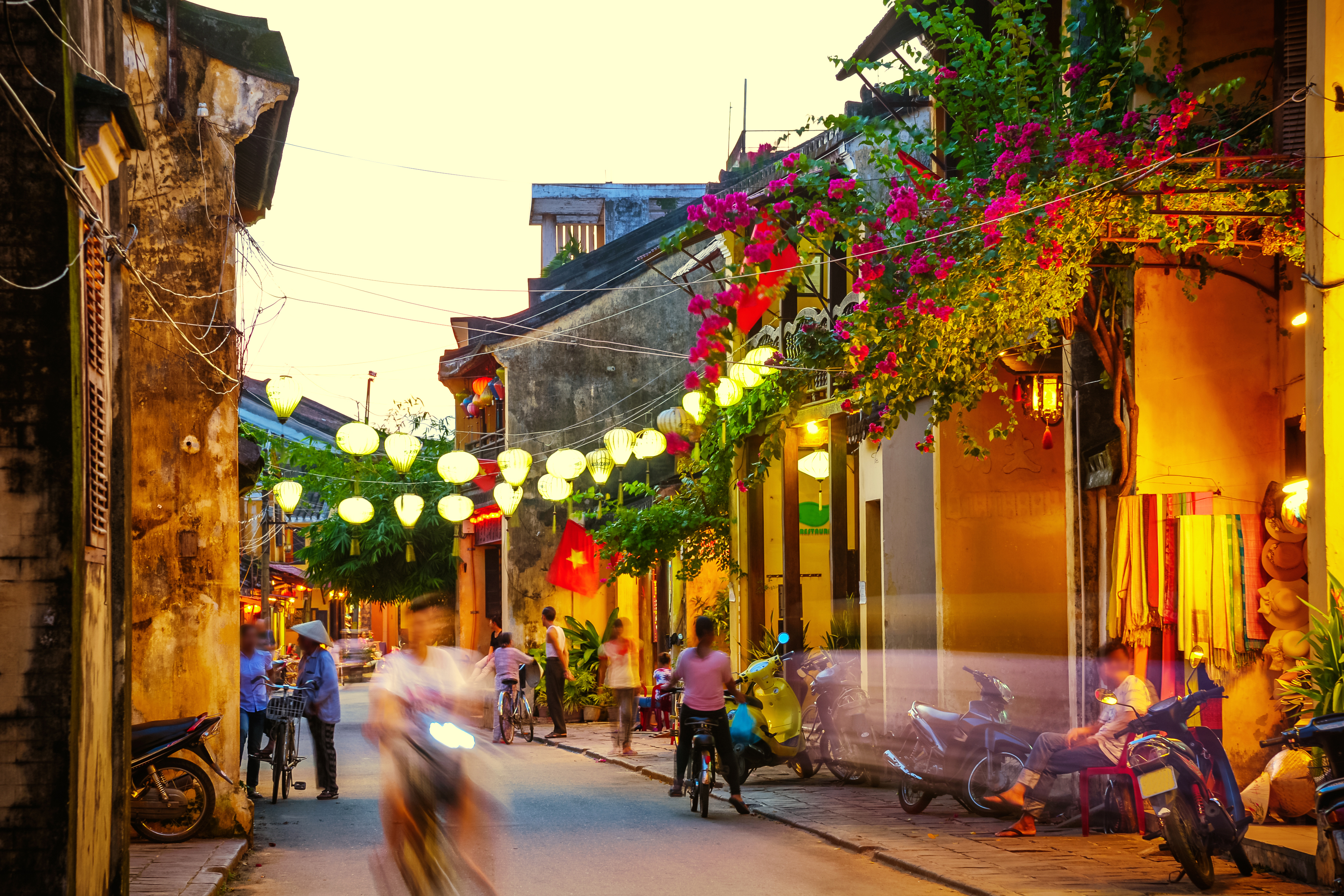 Hoi An street, lanterns, motorbikes, people chatting, buildings, plants 