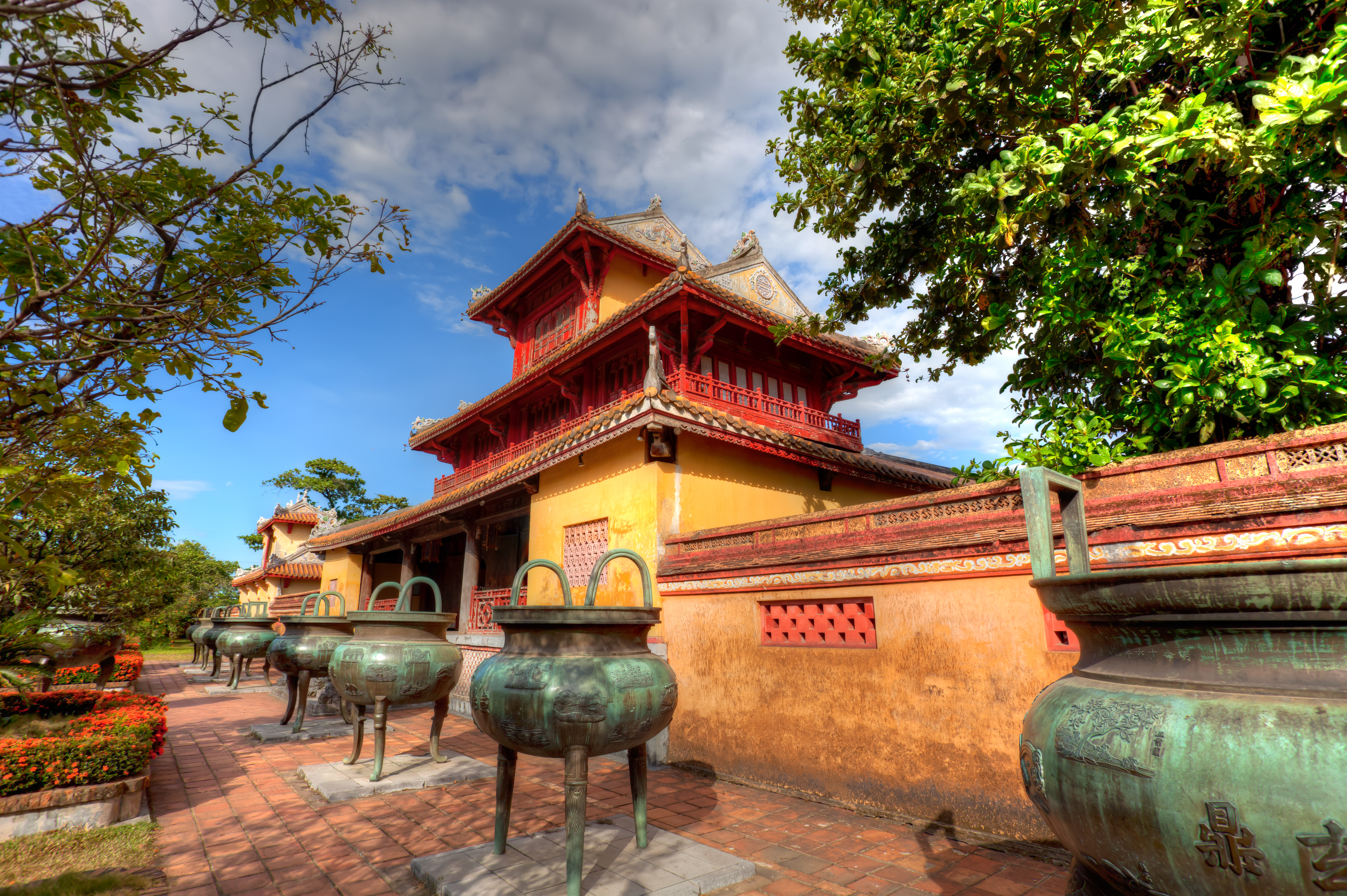 Part of the Imperial Palace in Vietnam, exterior, traditional architecture, red details, yellow walls, large stone vases