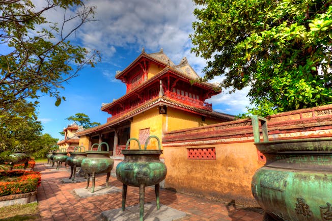 Part of the Imperial Palace in Vietnam, exterior, traditional architecture, red details, yellow walls, large stone vases