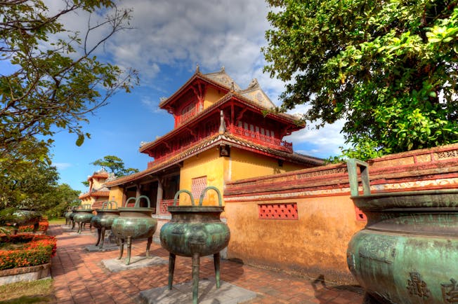 Part of the Imperial Palace in Vietnam, exterior, traditional architecture, red details, yellow walls, large stone vases