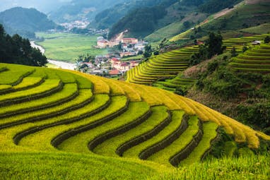 Terraced rice fields on slopes of mountains, valley with village in background