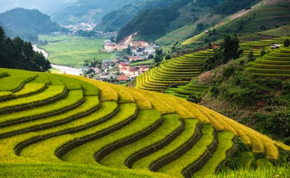 Terraced rice fields on slopes of mountains, valley with village in background