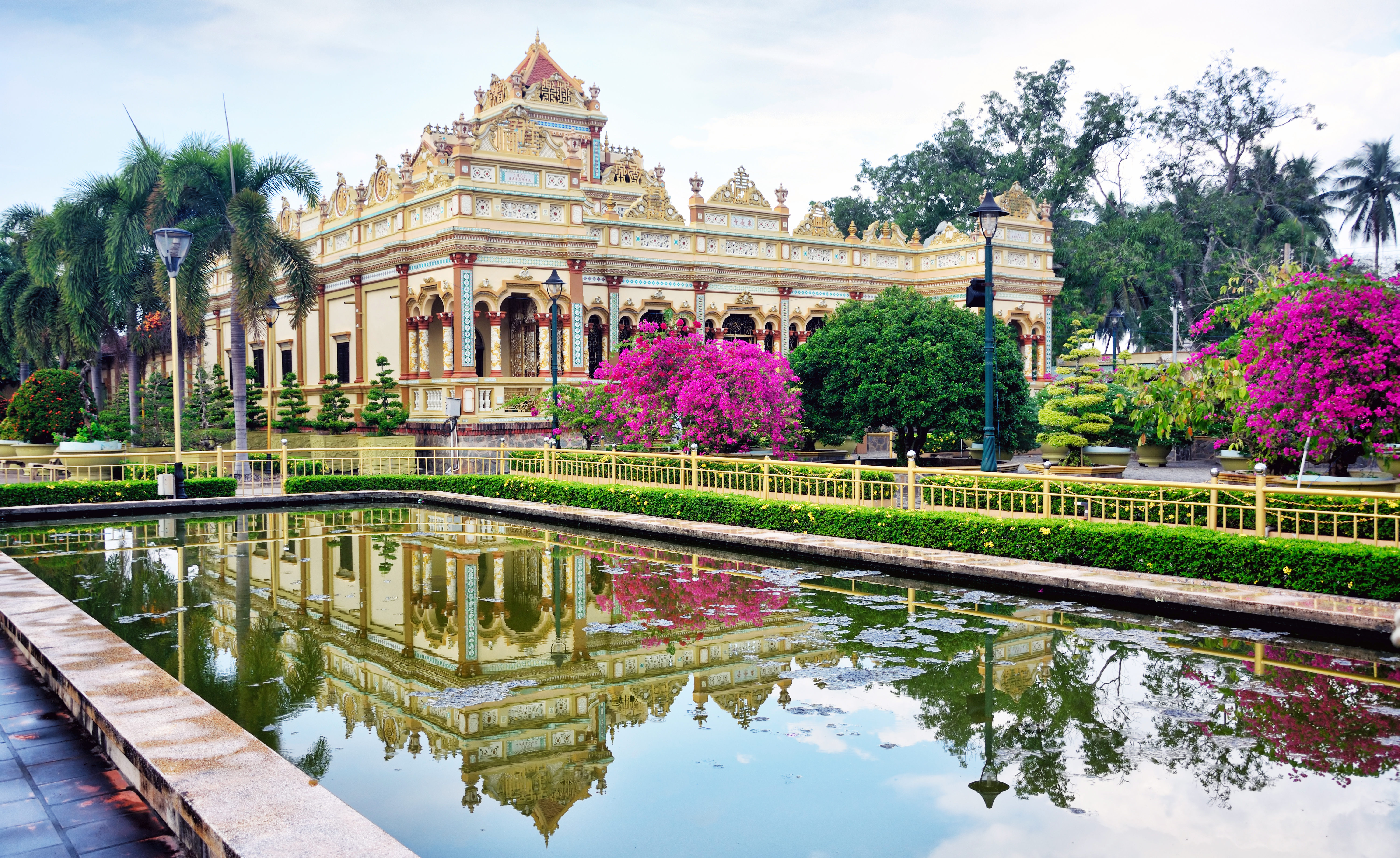 Vinh Trang Temple, pond, trees, pink flowers, intricate architecture, columns, temple facade