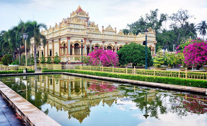 Vinh Trang Temple, pond, trees, pink flowers, intricate architecture, columns, temple facade
