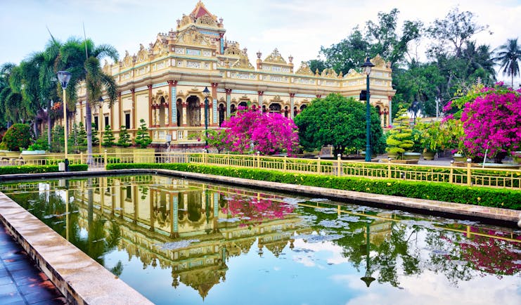 Vinh Trang Temple, pond, trees, pink flowers, intricate architecture, columns, temple facade